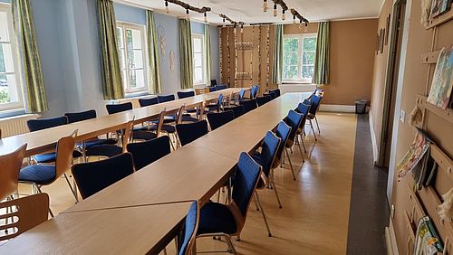 langer Raum mit 2 Tischreihen und einer großen Fensterfront