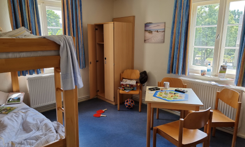 Jugendherbergszimmer mit Doppelstockbett, Tisch und Schrank und großen Fenstern